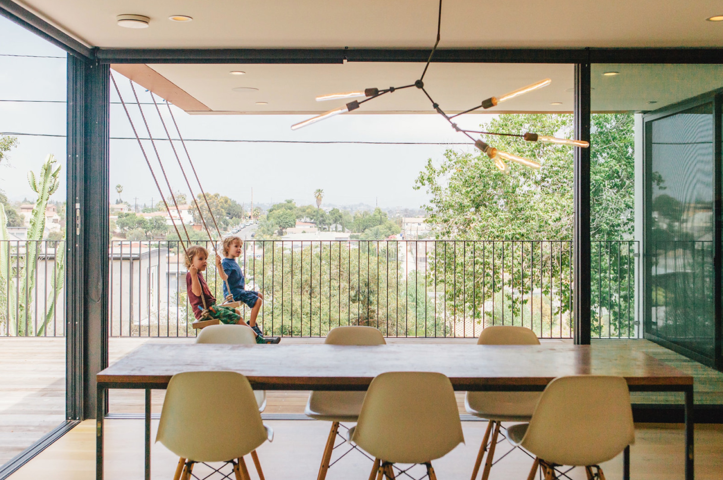 Children on rope swings beside the dining table, open to the terrace