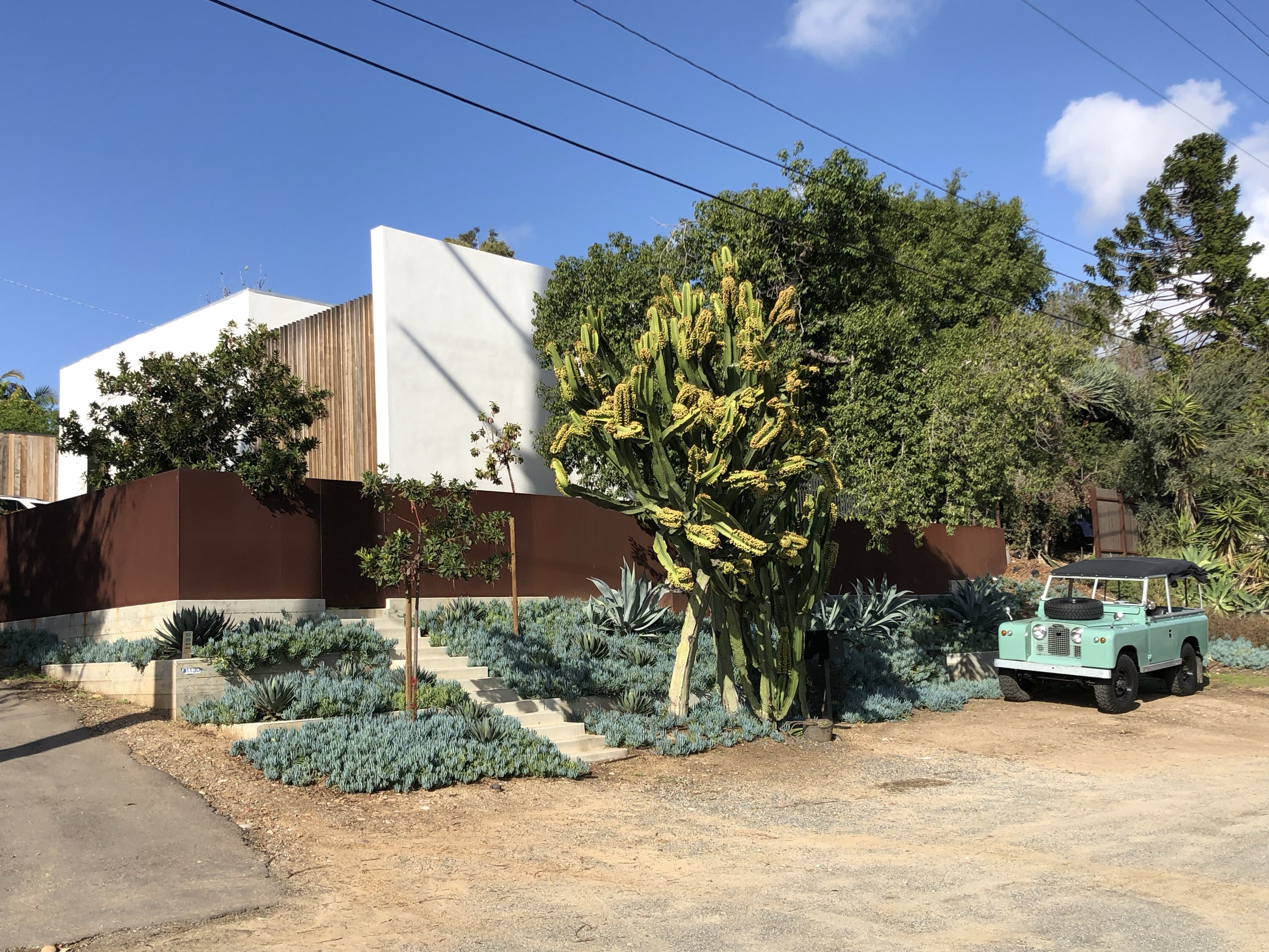 Street view with corten walls, succulent slope, and a Land Rover