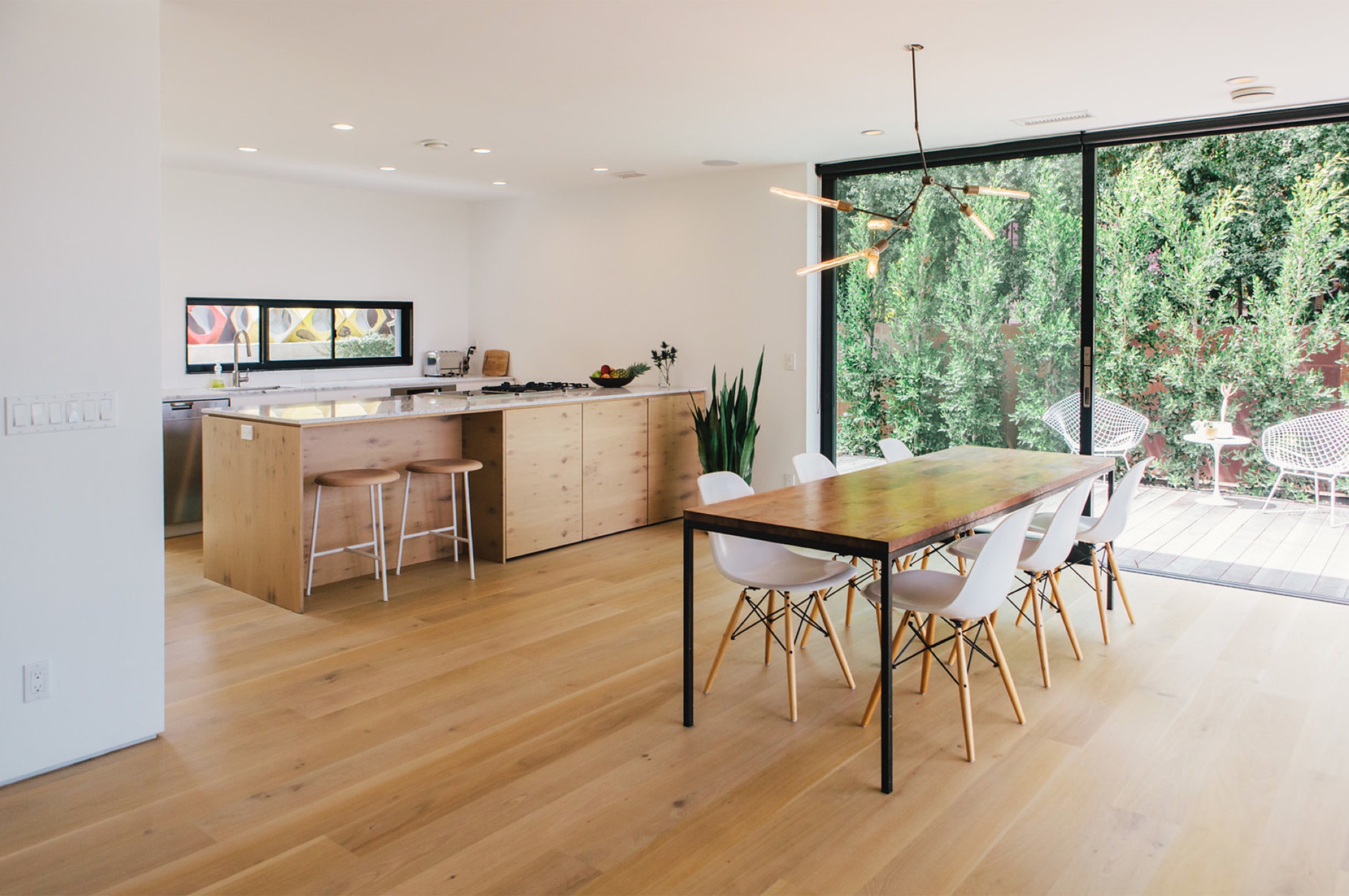 Open kitchen and dining with oak island and glass wall to the deck