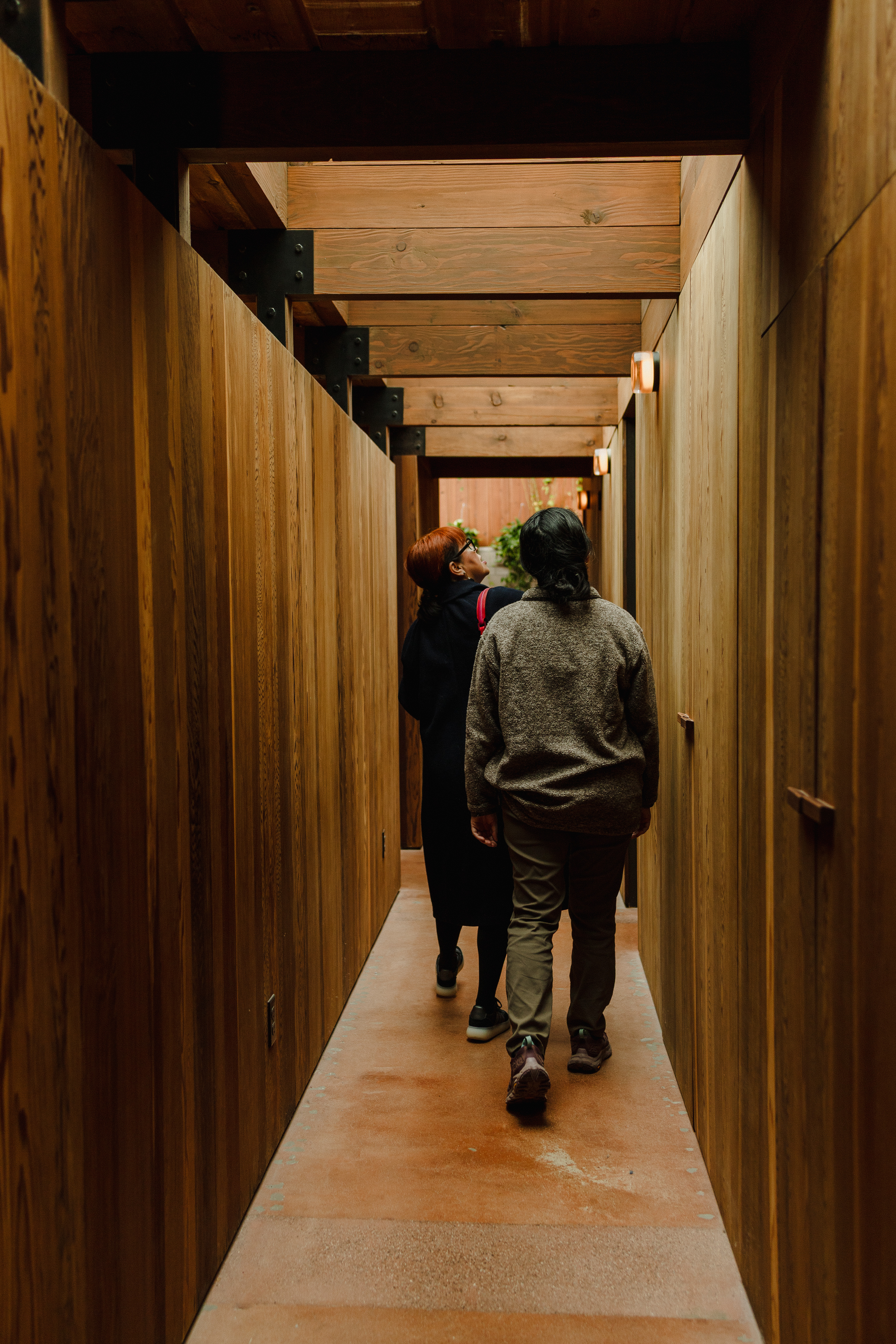 Two people walking through redwood hallway